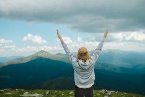 woman rise hand up on top of mountain and sunset